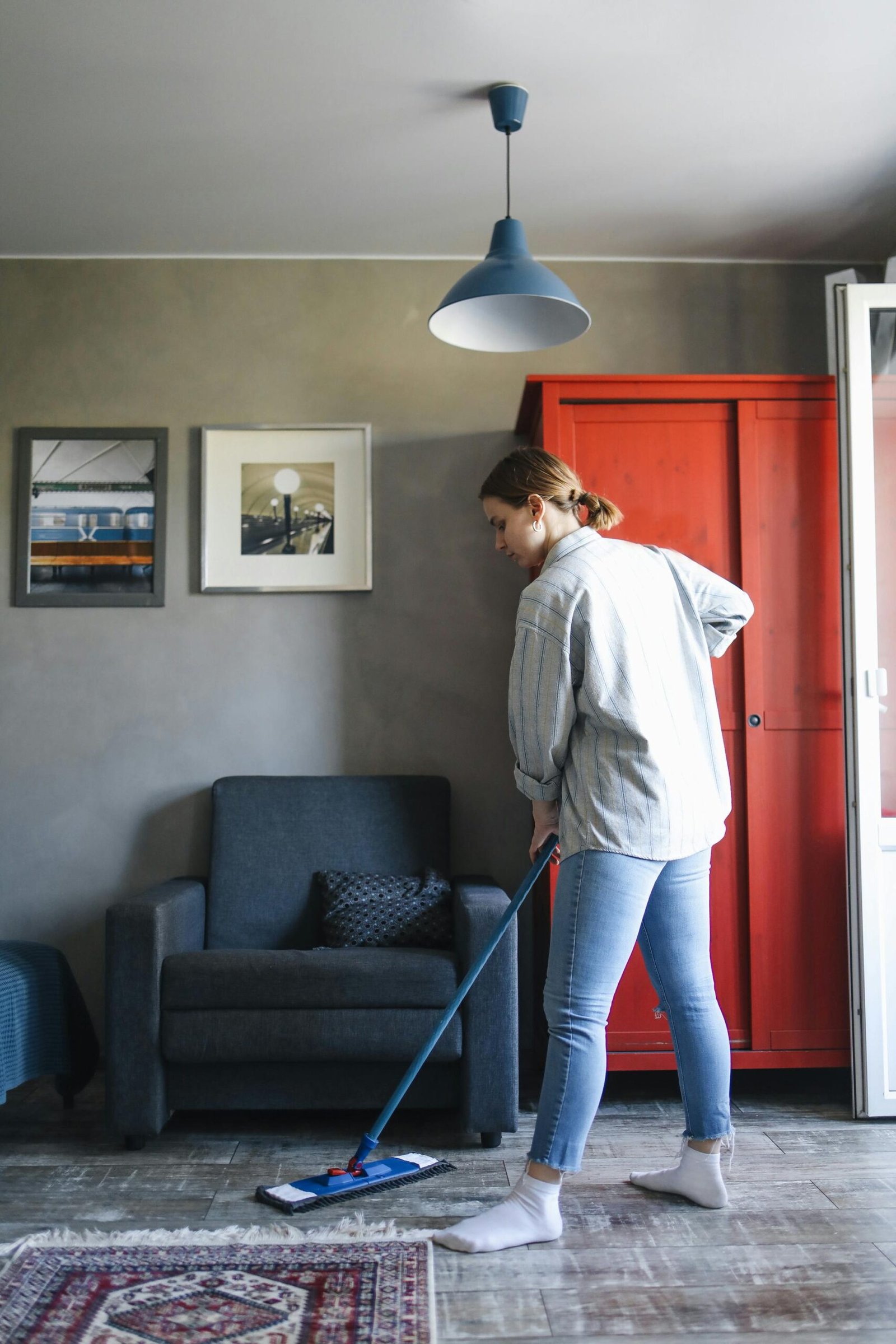 Woman cleaning the living room floor with a mop, showcasing a tidy home interior.