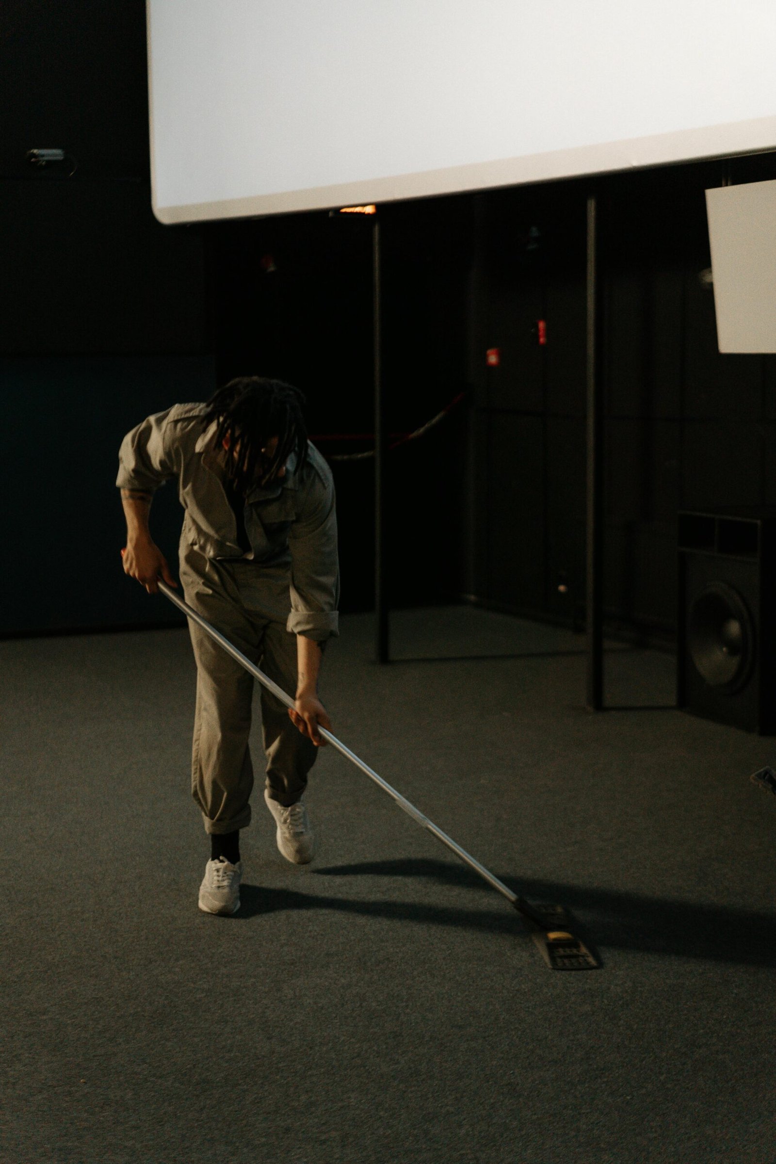 A person cleaning the carpet in an empty cinema, highlighting maintenance work.